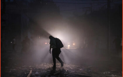 Foto dal New York Times a corredo dell'articolo del militare israeliano. Un uomo si fa strada lungo una strada disseminata di detriti di notte dopo gli attacchi aerei israeliani sulla città di Gaza sabato.